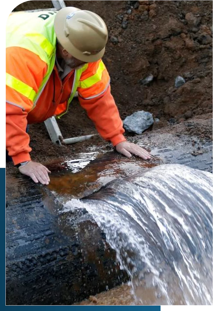 Worker inspecting a pipeline for signs of water leakage